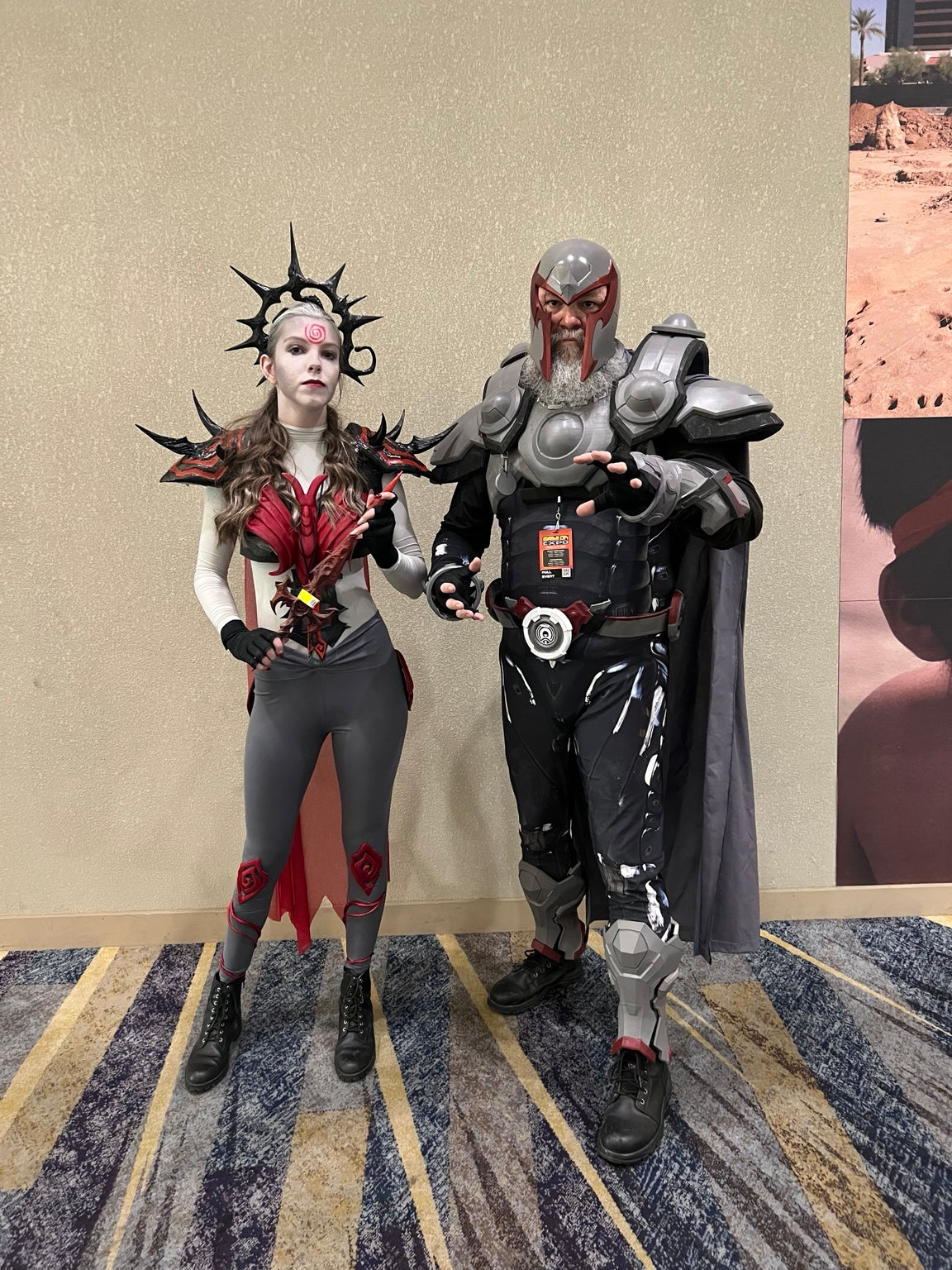 Two cosplayers wearing detailed armor and headpieces at a convention