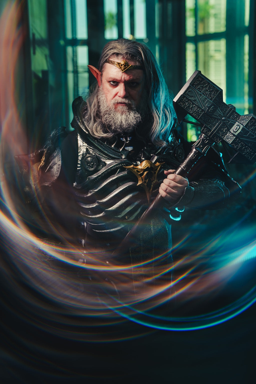 Cosplayer in detailed dark fantasy armor holding a large prop hammer